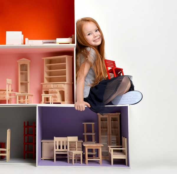 Happy little girl playing doll house filled with mini furniture toys Stock Photo 01