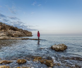 Lonely woman posing on rocky calm beach Stock Photo