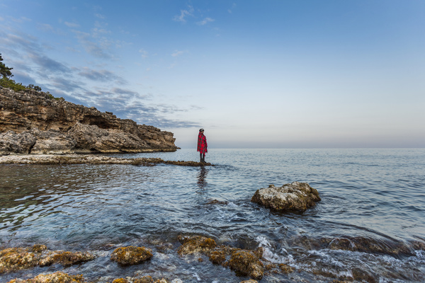 Lonely woman posing on rocky calm beach Stock Photo