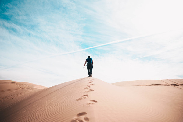 Man walking alone on dune Stock Photo
