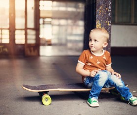 The little boy sitting on the skateboard Stock Photo