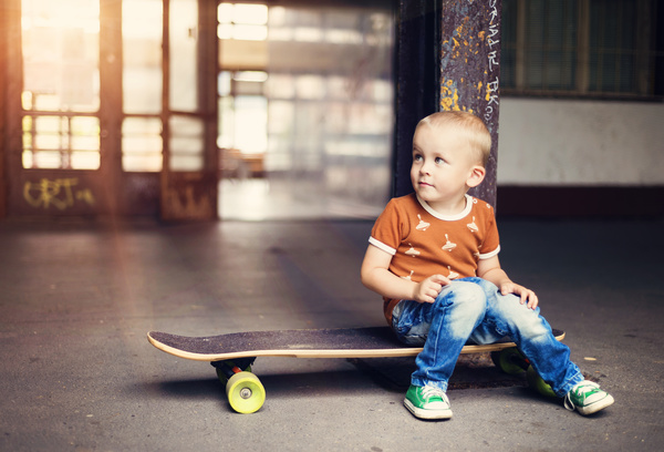 The little boy sitting on the skateboard Stock Photo