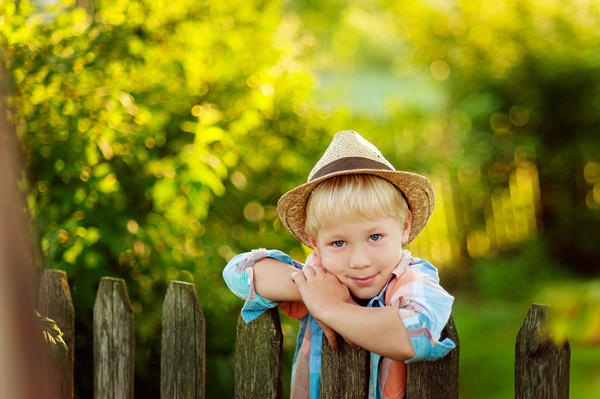 The little boy standing next to the fence Stock Photo
