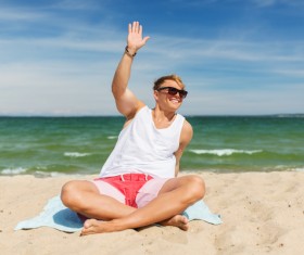 The man sitting on the beach waved his hand Stock Photo