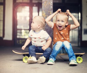 The two little boys sitting on the skateboard Stock Photo