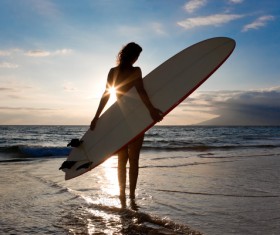 The woman holding the surfboard stands on the beach Stock Photo