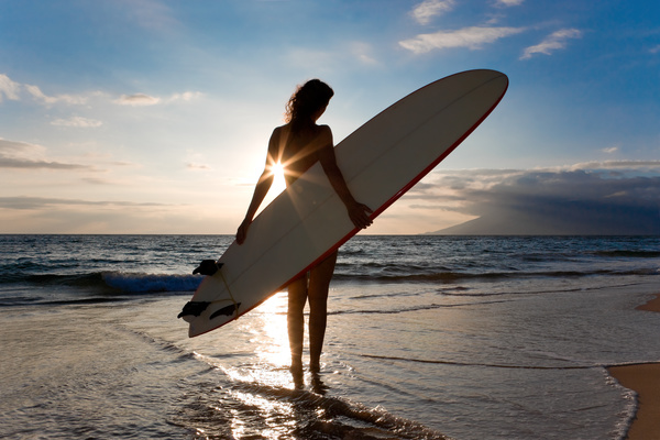 The woman holding the surfboard stands on the beach Stock Photo