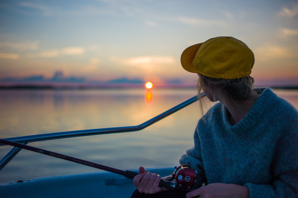 Young woman fishing on lake at sunset Stock Photo