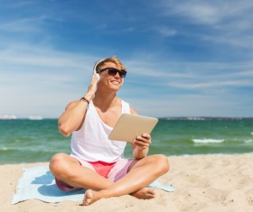 man sitting on the beach listening to music with a Tablet PC Stock Photo