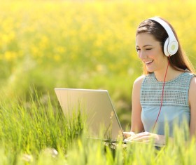 Happy girl on the grass using computer online chat Stock Photo