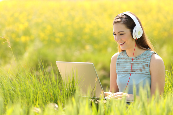 Happy girl on the grass using computer online chat Stock Photo