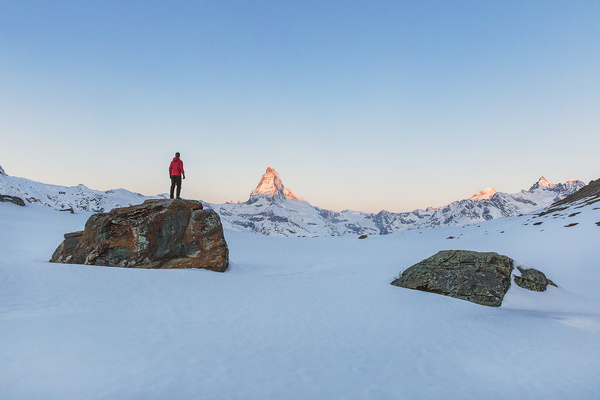 Man standing on rocky snow mountain Stock Photo