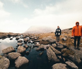 Men standing on calm lake stones Stock Photo