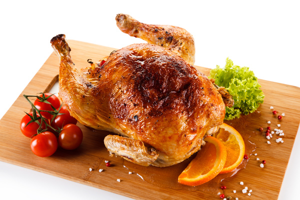 Roasted whole chicken with tomatoes on the chopping block Stock Photo