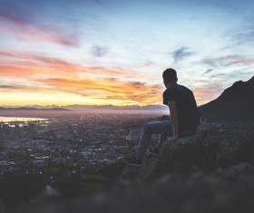 Sitting on the mountain to see the city scenery of the man Stock Photo