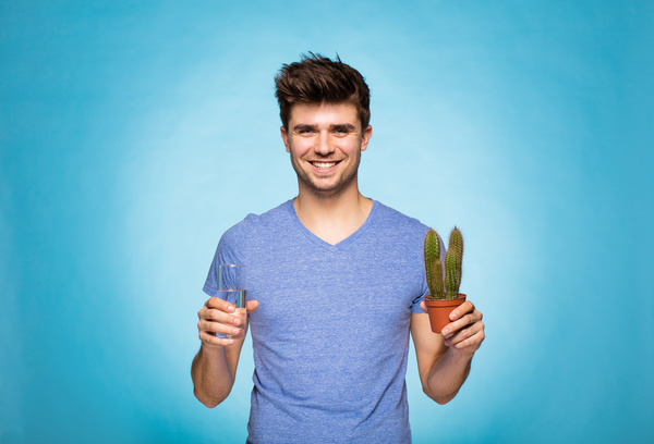 Smiling man ready to water the cactus Stock Photo