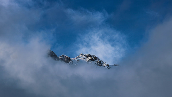 Thick cloud covering snowy peak Stock Photo