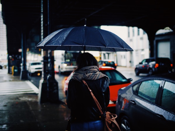 Woman walking under rainy weather with umbrella Stock Phot