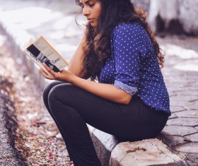 Young woman reading book on pavement Stock Photo