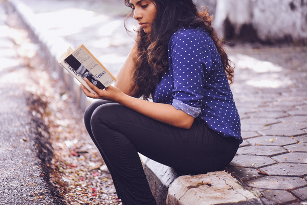 Young woman reading book on pavement Stock Photo