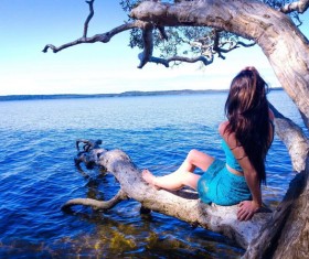 at the lake on a tree trunk woman Stock Photo