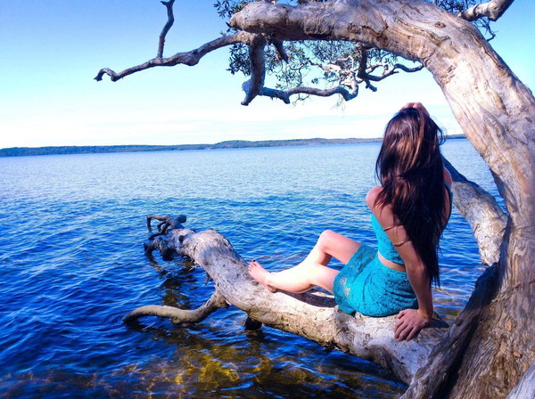 at the lake on a tree trunk woman Stock Photo