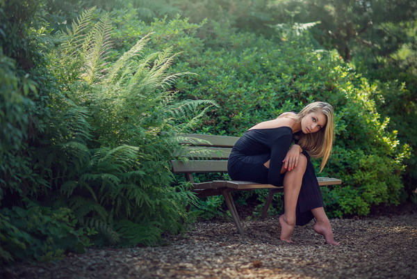 Beautiful girl sitting on a bench outdoors Stock Photo