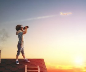 Children on the roof with a telescope to see the plane Stock Photo