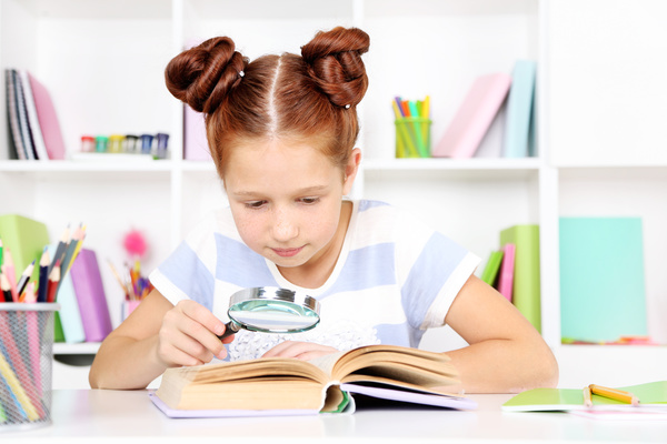 Children reading books with magnifying glass Stock Photo