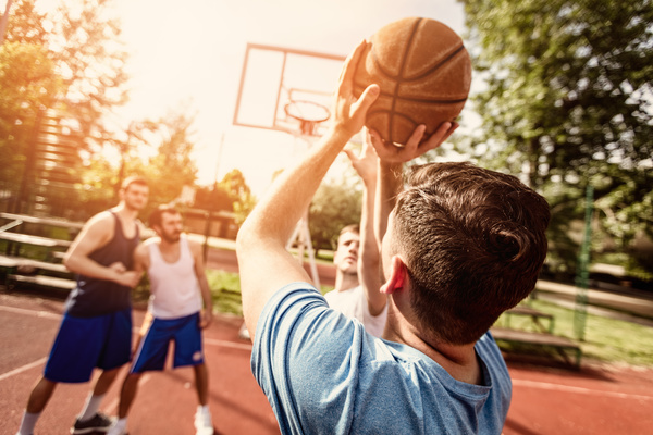 Friends playing ball in the open basketball court Stock Photo