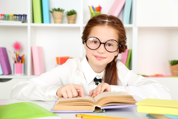 Little girl reading with glasses Stock Photo
