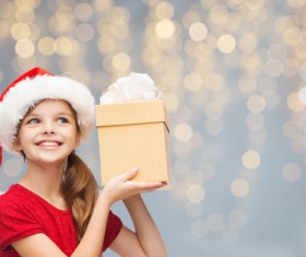 Little girl wearing a christmas costume is holding gift box