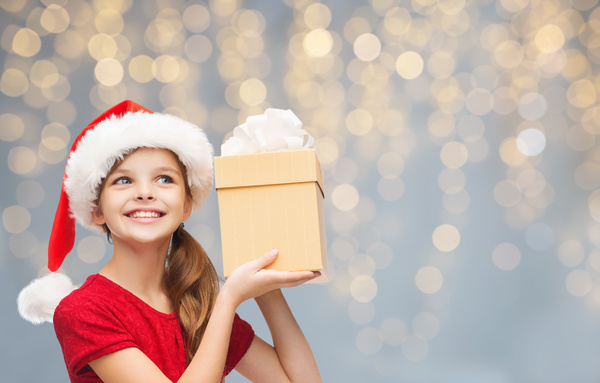 Little girl wearing a christmas costume is holding gift box