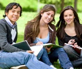 Male and female students sitting in the grass Stock Photo 01