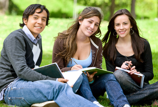 Male and female students sitting in the grass Stock Photo 01