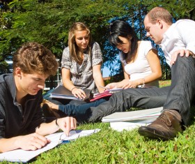 Male and female students sitting in the grass Stock Photo 02