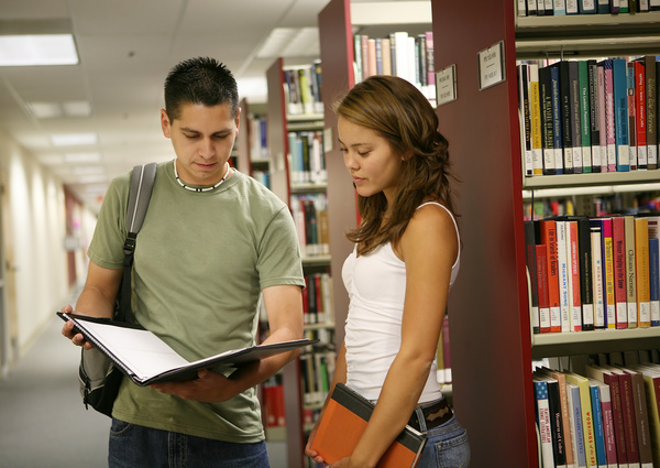 Male and female students talking in the library Stock Photo