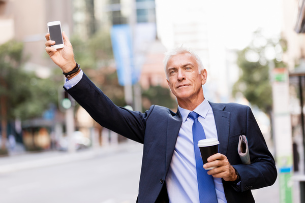 Man holding cellphone and coffee takes taxi Stock Photo