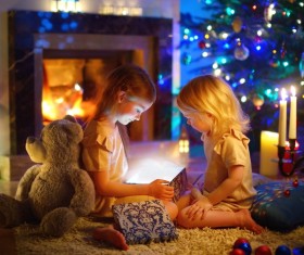 Open gift box under Christmas tree Little Sisters Stock Photo