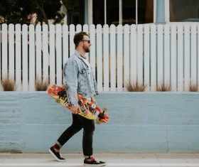 Stylish man walking with skateboard Stock Photo