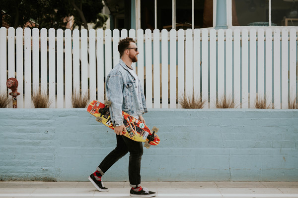 Stylish man walking with skateboard Stock Photo