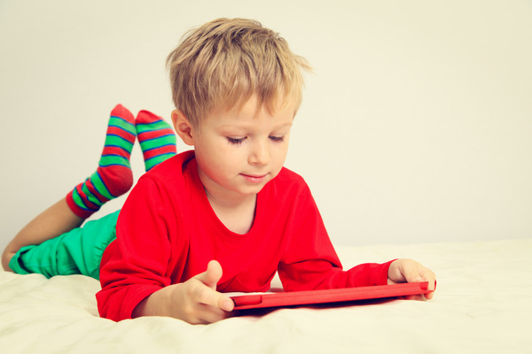 The little boy who plays the game on the bed Stock Photo