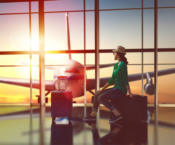 Woman sitting in suitcase looking at the plane in the distance Stock Photo