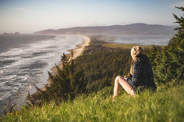 Woman sitting on the hillside watching the sea Stock Photo