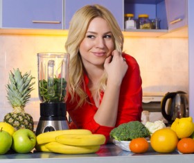 Woman squeezing juice in the kitchen Stock Photo