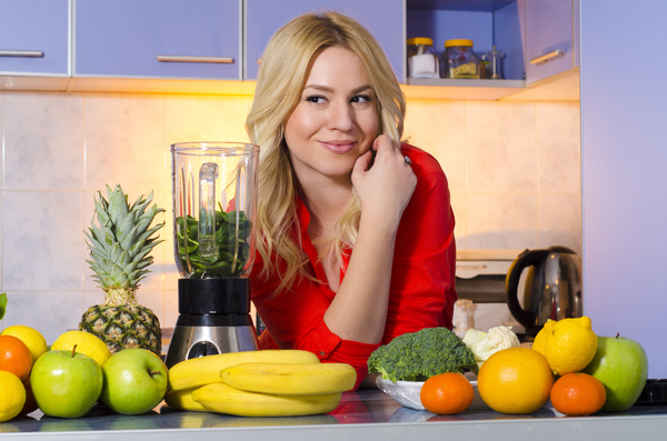 Woman squeezing juice in the kitchen Stock Photo