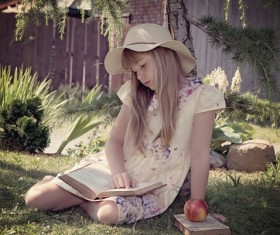 little girl sitting on the grass reading Book Stock Photo