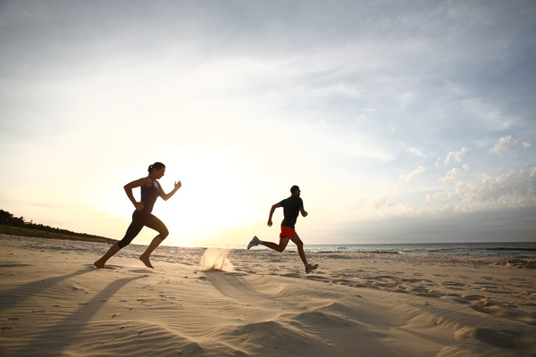 man and woman running on the beach Stock Photo