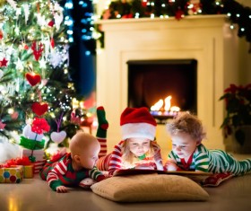 Children watching video in front of the Christmas tree Stock Photo 01