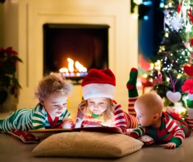 Children watching video in front of the Christmas tree Stock Photo 02